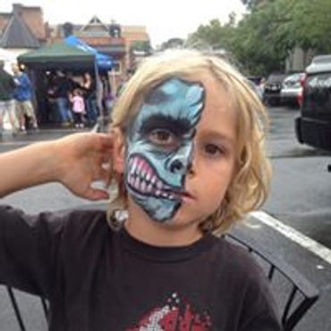 Child with half-face blue monster face paint.