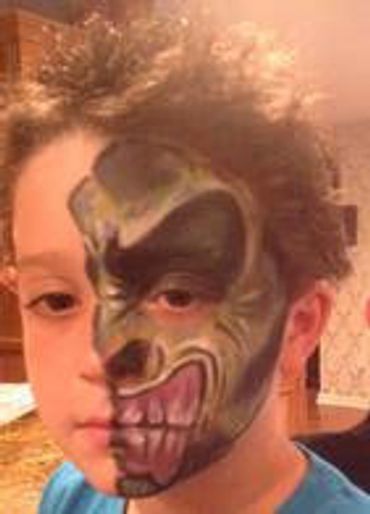 Child with half face painted as a monster.