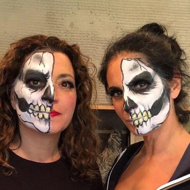 Two women with half-face skeleton makeup.