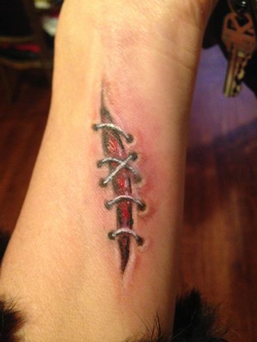 3D tattoo of a stitched wound on wrist.