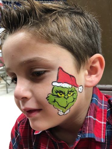 Boy with Grinch face paint and Santa hat.