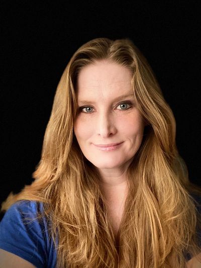 Smiling woman with long blonde hair wearing a blue shirt.