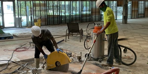 Concrete cutting via concrete sawing in a commercial building lobby. Two ACCG, Inc. workers.