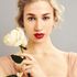 girl with blonde hair up with red lips holding a white rose 