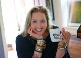 Smiling woman holding a mug that says 'Good Vibes'.