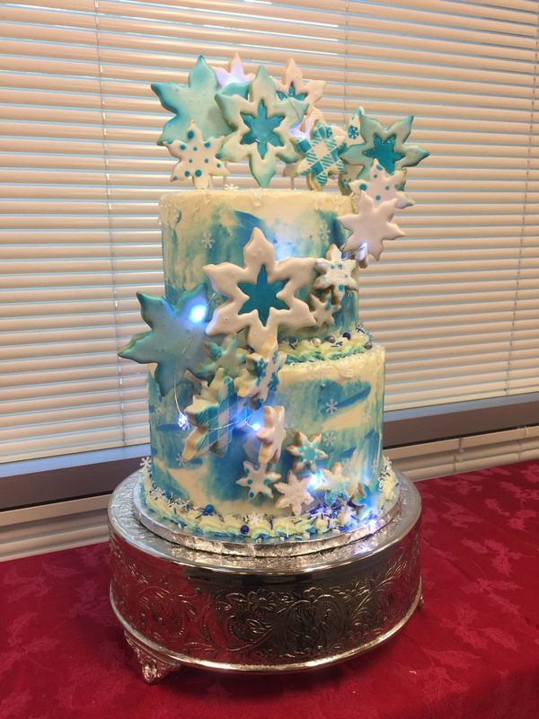 2 tier white and blue cake with white and blue cookies cascading down the side