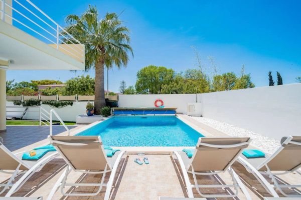 Modern backyard with swimming pool and loungers.