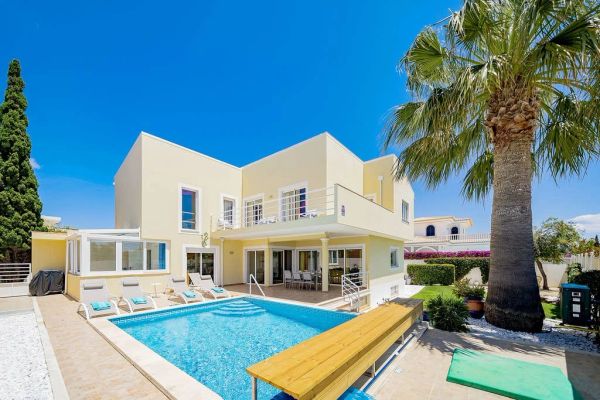 Modern two-story house with a pool and palm trees.