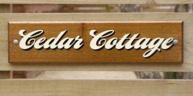 Simple timber property sign for an Airbnb rental in Moama. Cedar Cottage handpainted on timber.