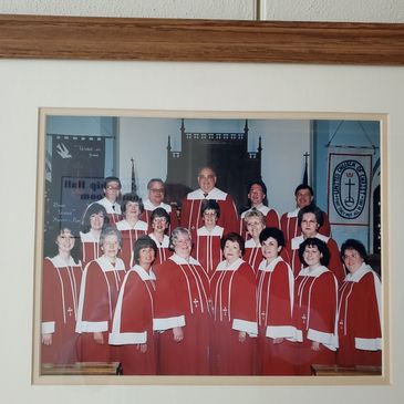 A church choir group wearing red robes posing for a photo inside a church.