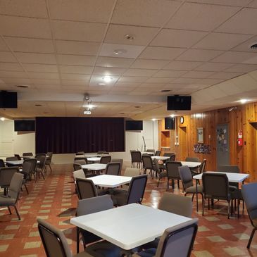 Empty community hall with tables and chairs arranged.