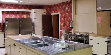 Vintage kitchen with floral wallpaper and large metal refrigerators.