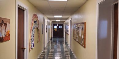 A clean, well-lit hallway with artwork and bulletin boards on the walls.