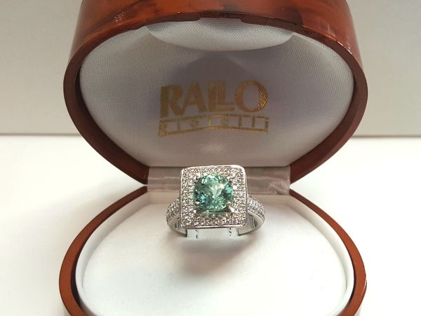 Elegant silver ring with green gemstone in a velvet box.