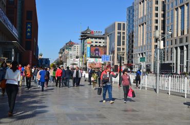 Busy urban street with people walking under clear blue sky.
