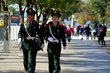 Two uniformed officers walking confidently down a tree-lined street.