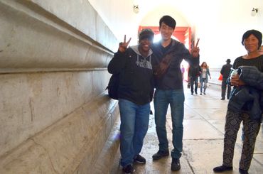 Two friends posing with peace signs in a bright hallway.