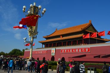 Crowd gathers at Tiananmen Gate with Chinese flags and a portrait of Mao Zedong.