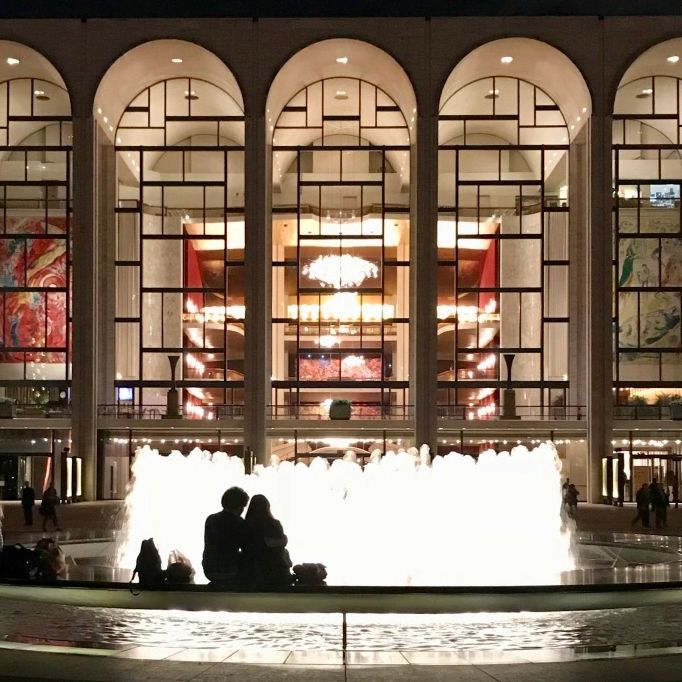 couple and fountain in front of illuminated Metropolitan Opera