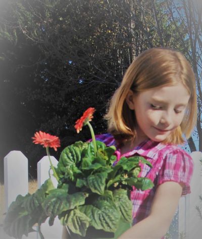 Girl holding flowers grown in garden.