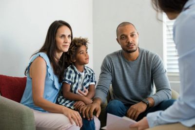 A family attentively listening to a counselor in a therapy session.