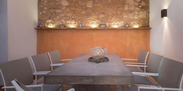 Minimalist dining area with concrete table and modern chairs under warm lighting.