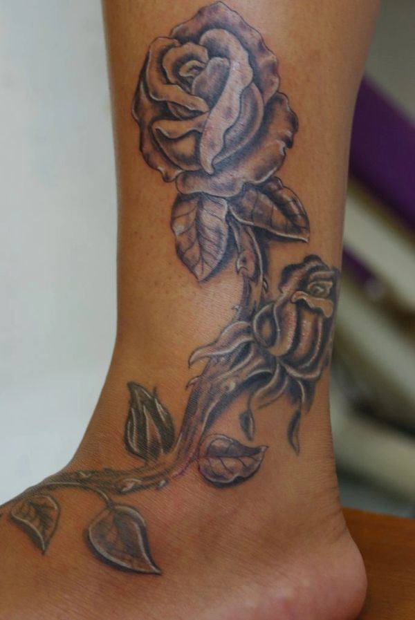 Black and grey rose tattoo on a woman's lower leg.