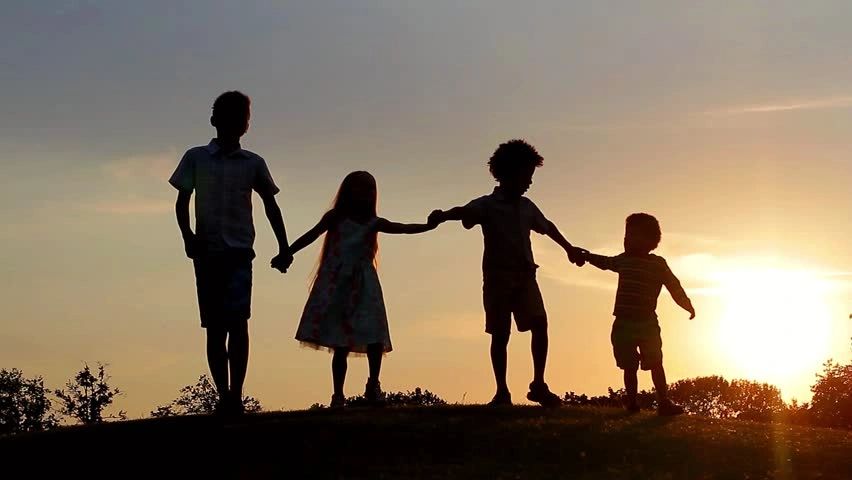 Silhouette of four kids holding hands during sunset