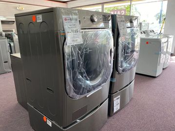 Two modern front-load washers or dryers displayed in a store.