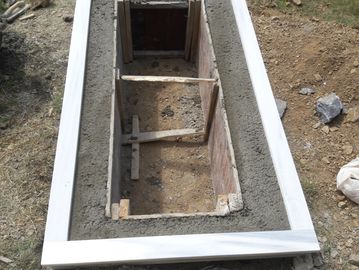 Concrete foundation with a rectangular wooden formwork inside.