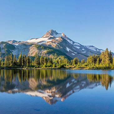 Snow-capped mountain reflected in a calm lake.