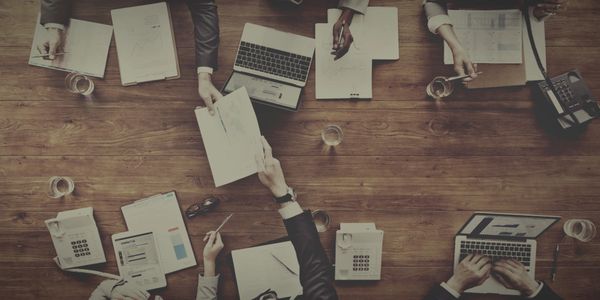 image looking down on a conference table with two people exchanging paperwork.