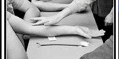 People showing their outstretched arms on a table.