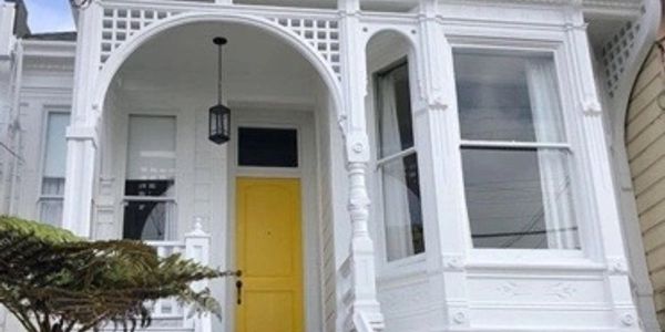 White monochromatic Victorian home with bright yellow door