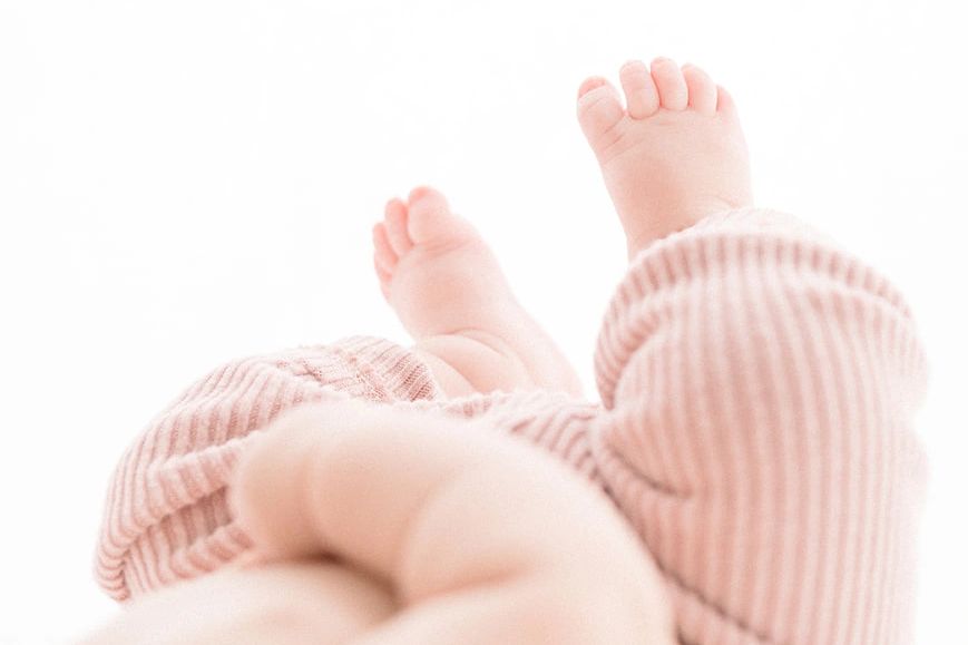 baby photography tiny toes baby laying down wearing soft pink pants