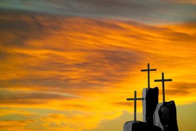 Three crosses against clouds and sun.