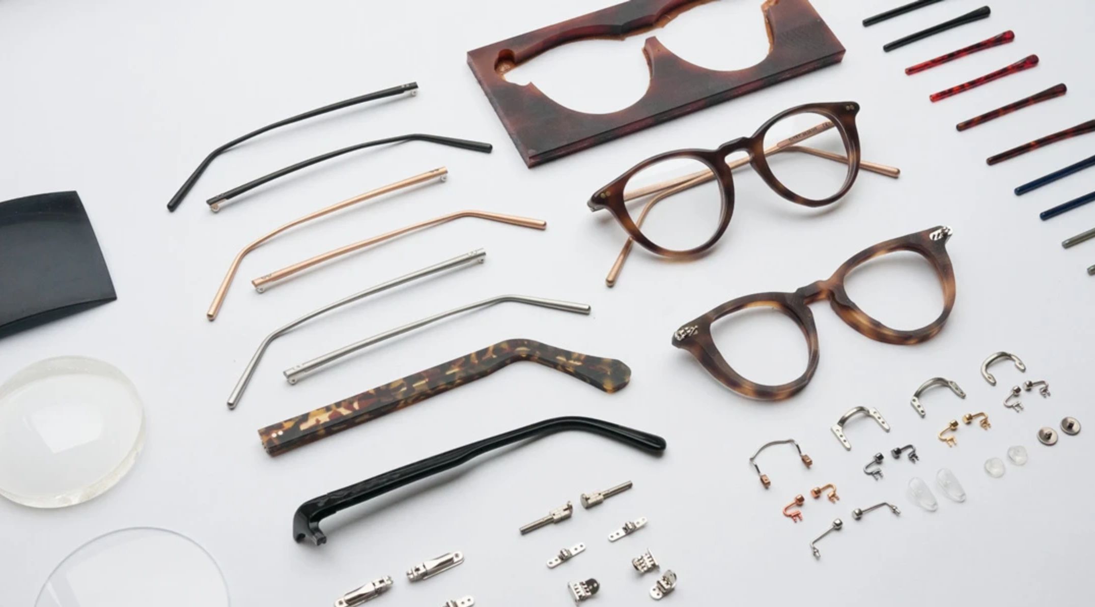Assortment of eyeglass frame parts placed on a white background.