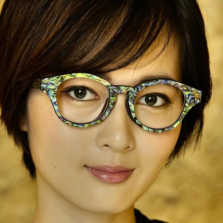 A woman wearing custom eyeglasses made of shell and wood