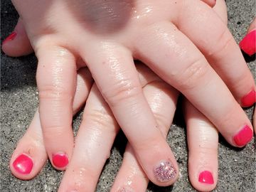 Bright red kid's nails with light pink sparkle party nail at the beach with sandy background - kid's