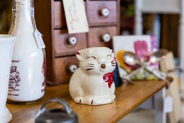Yawning cat porcelain with antique bottles and decor 