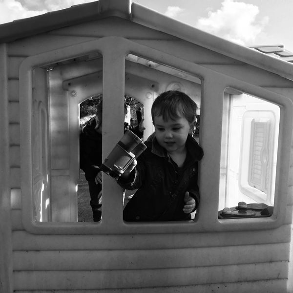 A child playing outside in the wendy house at playgroup. 