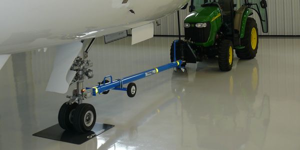 John Deere tractor hooked up to business jet with tow bar. 