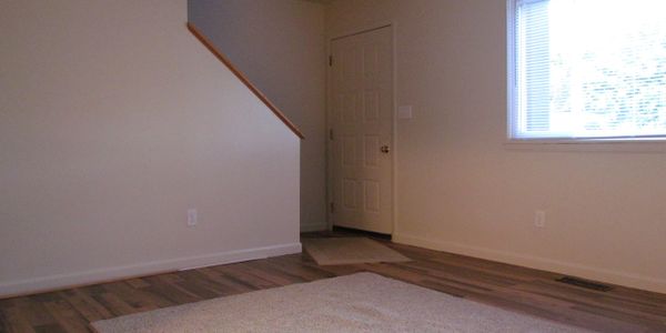 Empty room with wooden flooring and a window letting in natural light.