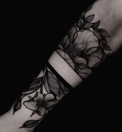 Black floral tattoo on forearm with a solid black band.