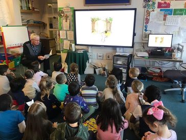 Teacher reading to a group of children in a classroom.